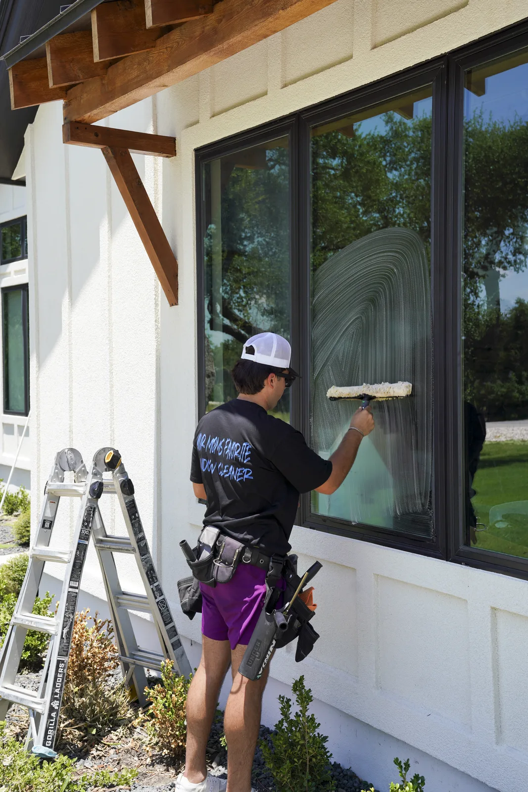 SudZup squeegeeing an upper window from a ladder